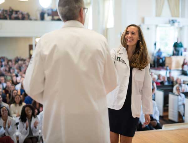 Dean page shaking student's hand at White Coat 2019