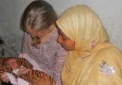 Two women looking at a newborn baby in Dhaka