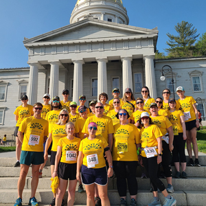 Group of runners in yellow jerseys on VT Statehouse steps