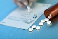 Image of a prescription being written next to a bottle of pills
