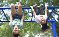 Two children upside down on the monkey bars