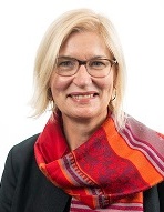 Dr. Sylvie Doublie in dark coat with bright red scarf smiling at camera