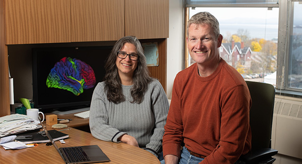 Hugh Garavan and Alexi Potter smiling while sitting at a desk.