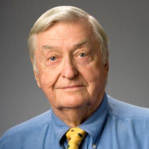 Headshot of man in blue shirt and yellow tie