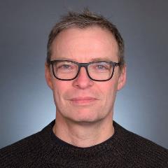 Headshot of Professor Jean Celli in black sweater, glasses, smiling