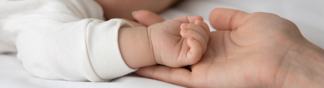 infant hand rests on parent palm