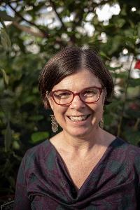 Leigh Knodler PhD headshot smiling, outside in the sun, glasses