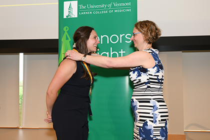 woman having award medallion hung around neck by another woman