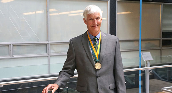 Tom Peterson wearing his medal with green and gold ribbon