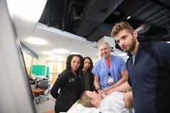 Group of physicans with patient on bed