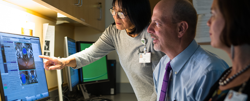 Three doctors looking at image on a computer.