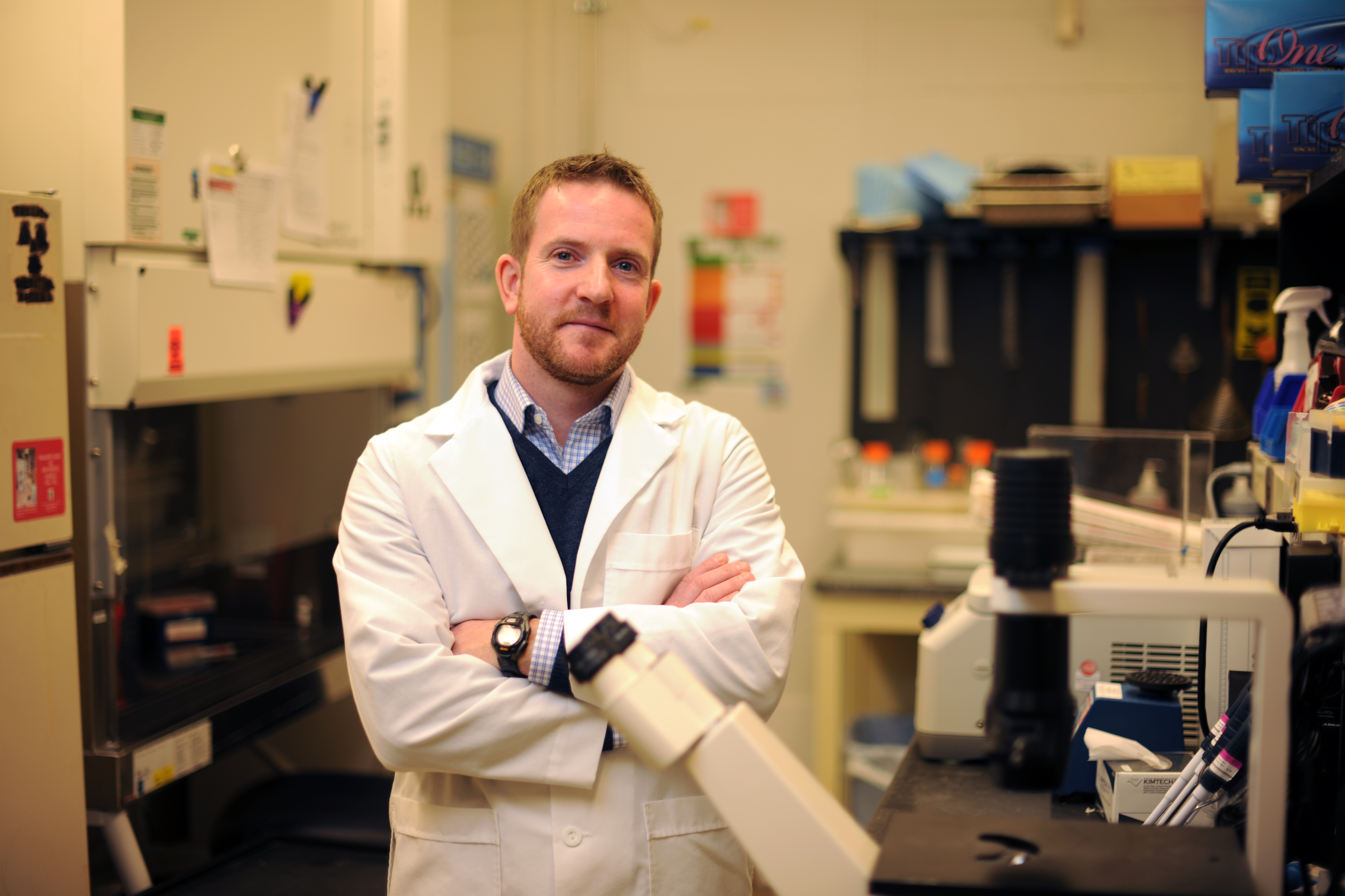 Male researcher in white coat standing in lab