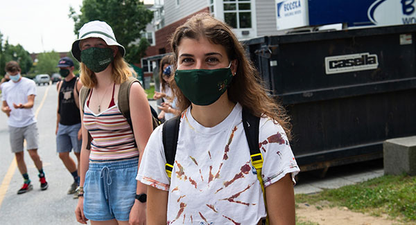 Two young women wearing green masks looking at the camera